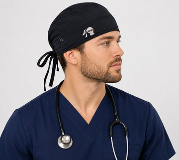 Ashtown Clothing black medical scrub hat with tie-back closure worn by a male healthcare professional