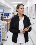 Ashtown Clothing black full-zip medical hoodie worn by a nurse over white scrubs in a hospital hallway