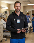 Ashtown Clothing unisex black full-zip medical hoodie worn by a male nurse with a stethoscope in a hospital setting.