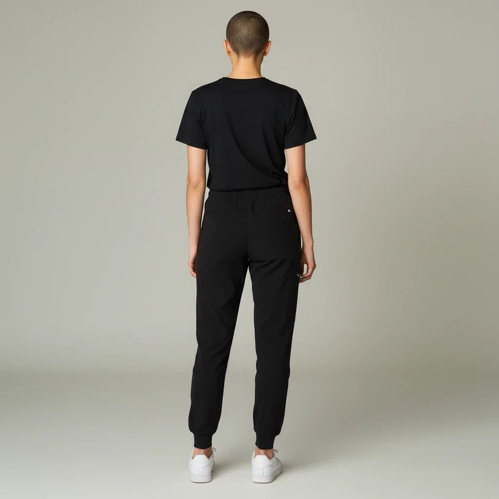 Back view of a model wearing Ashtown Clothing black petite performance jogger scrub pants with ribbed ankle cuffs.
