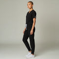 Model wearing Ashtown Clothing black petite performance jogger scrub pants with a matching v-neck scrub top.
