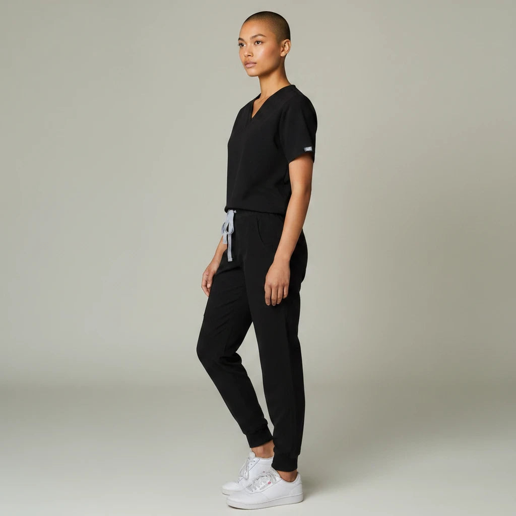 Model wearing Ashtown Clothing black petite performance jogger scrub pants with a matching v-neck scrub top.