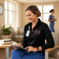 Ashtown Clothing black quarter-zip pullover with Blessed Nurse embroidery worn by a smiling nurse in a clinic