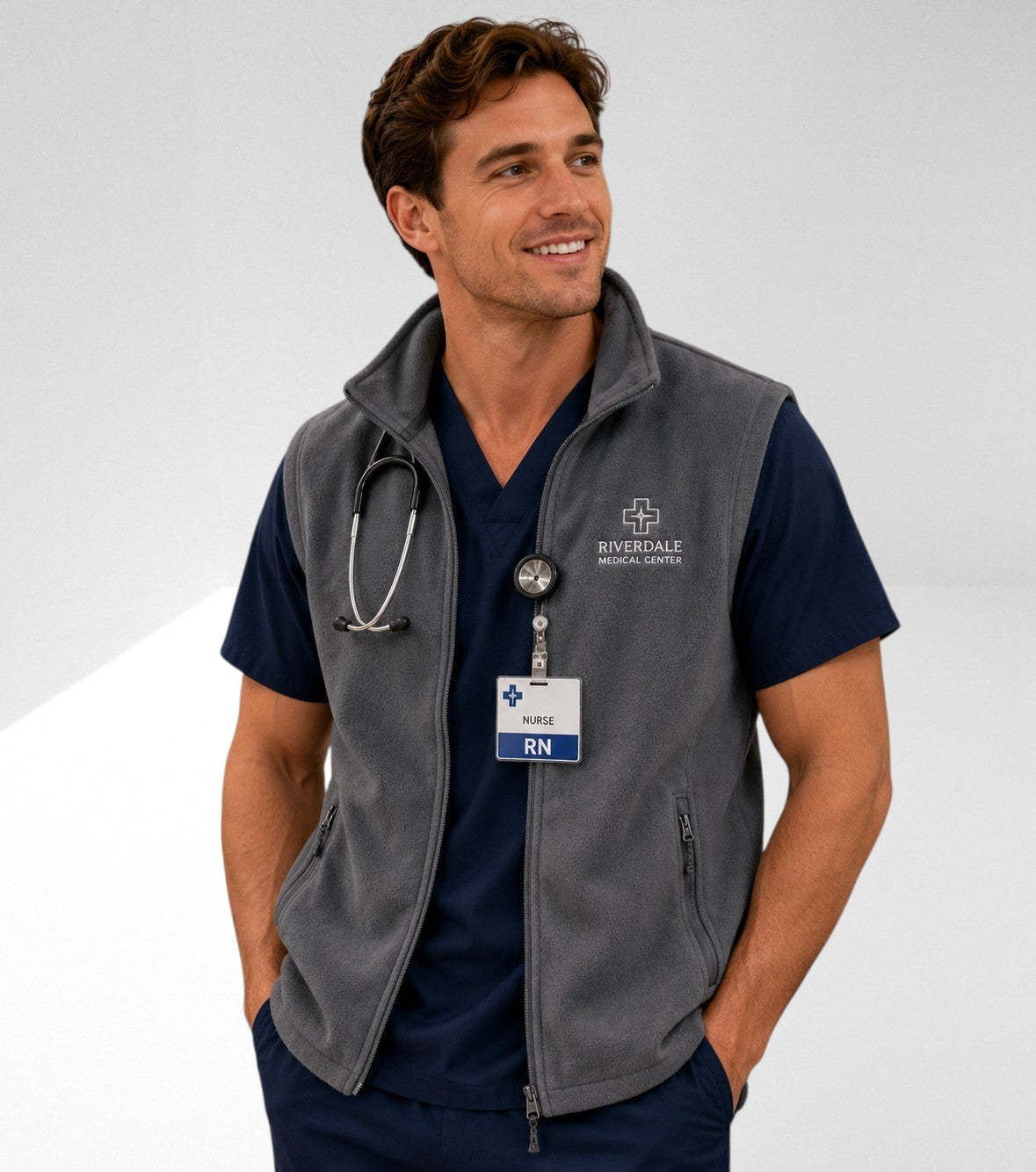Ashtown Clothing charcoal grey fleece vest with full zip worn by a male nurse in navy blue scrubs with a stethoscope.