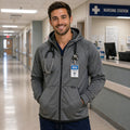 Male nurse wearing a grey Ashtown Clothing performance full zip hooded jacket with a stethoscope in a hospital hallway.