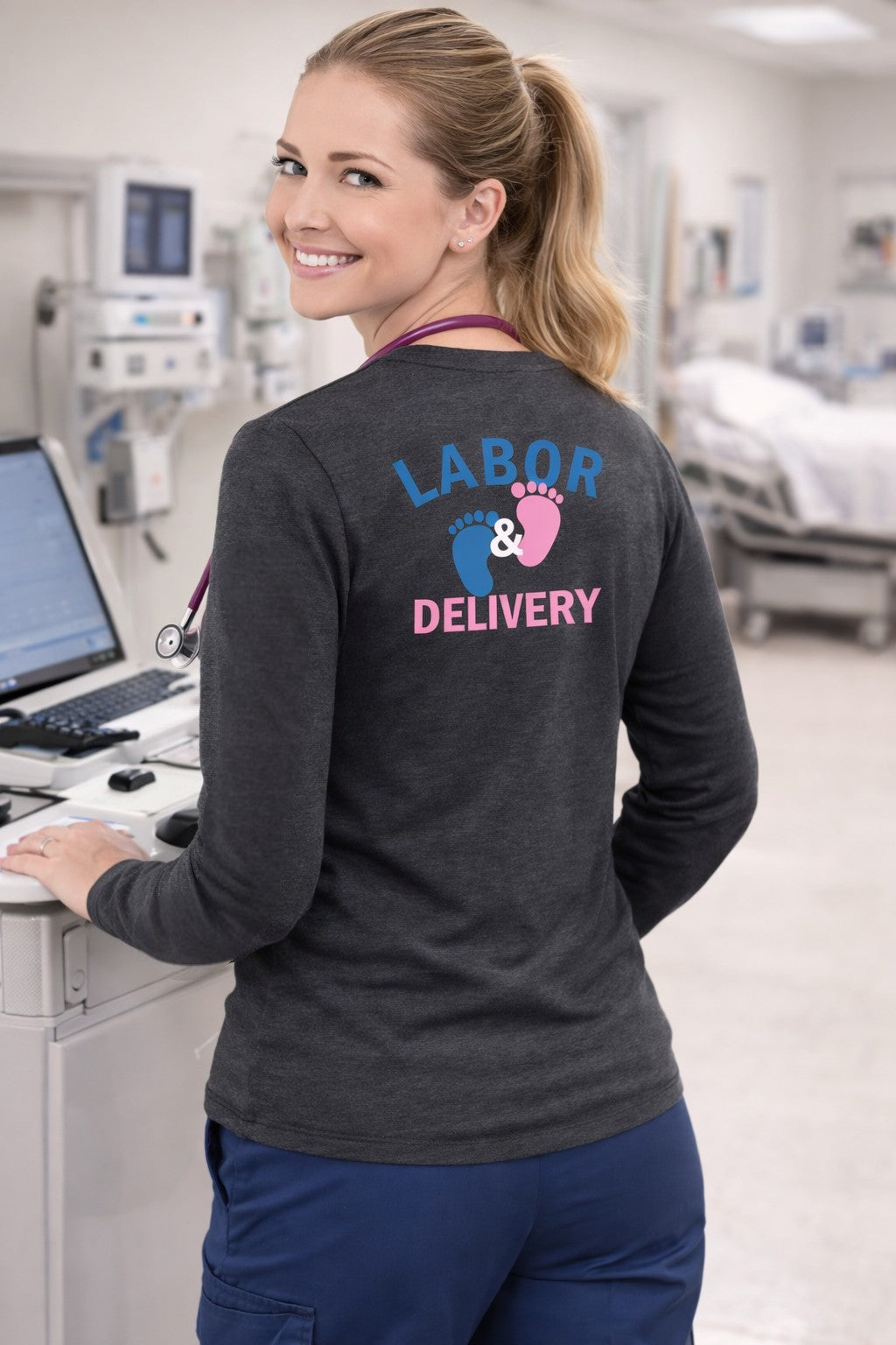 Ashtown Clothing charcoal grey long sleeve tee with Labor and Delivery baby footprint graphic worn by a nurse.
