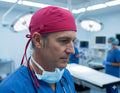 Ashtown Clothing professional medical scrub hat in magenta worn by a male surgeon in a hospital operating room