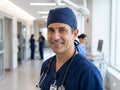 Ashtown Clothing navy blue medical scrub hat worn by a male healthcare professional in a hospital hallway